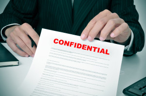 a man wearing a suit showing a document with the text confidential written in it